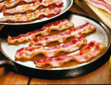 Hickory smoked bacon strips in a cast iron pan